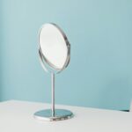 головна A minimalist scene with a round mirror on a white desk against a pastel blue wall, ideal for decor inspiration.