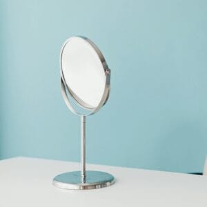 A minimalist scene with a round mirror on a white desk against a pastel blue wall, ideal for decor inspiration.
