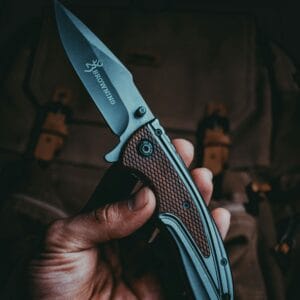 A detailed close-up view of a hand holding a sharp tactical knife, depicting precision and craftsmanship.